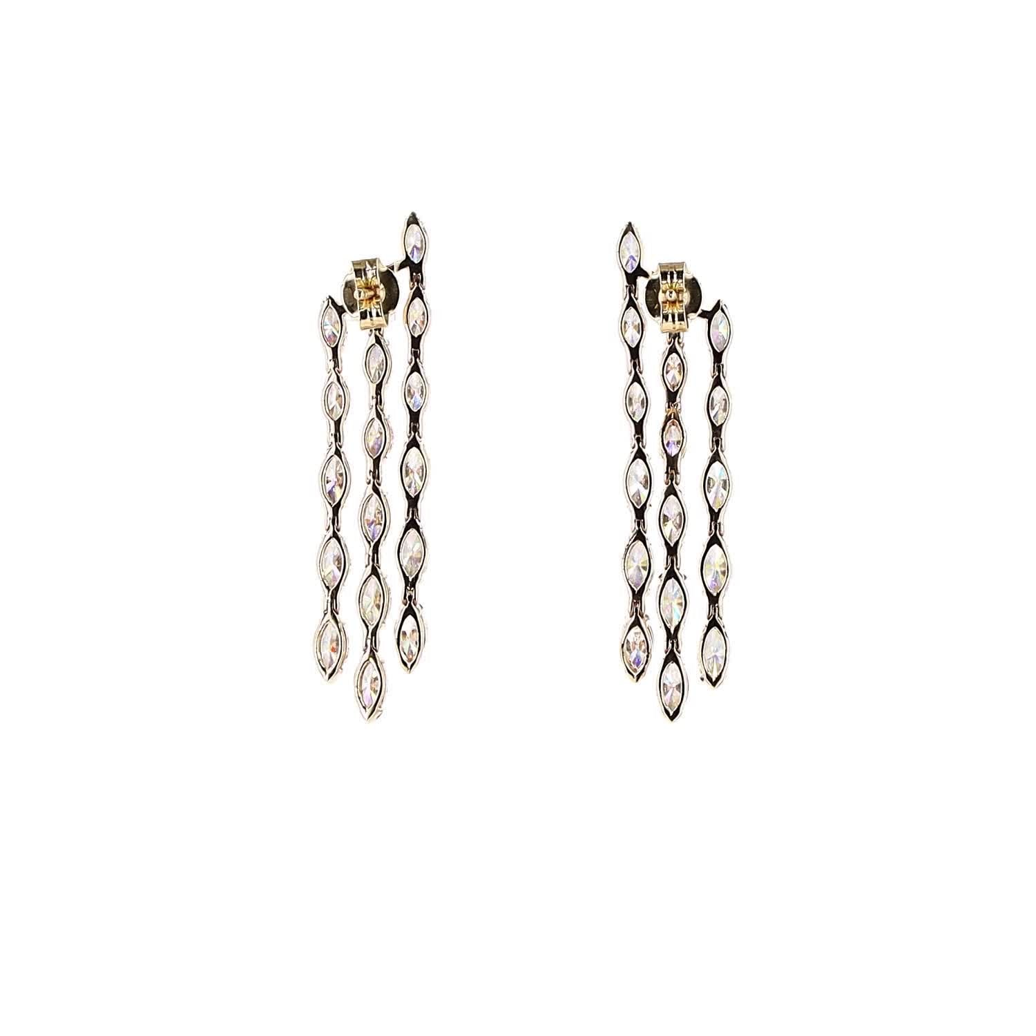 Pair of dangling earrings with gold and white diamonds on a white background